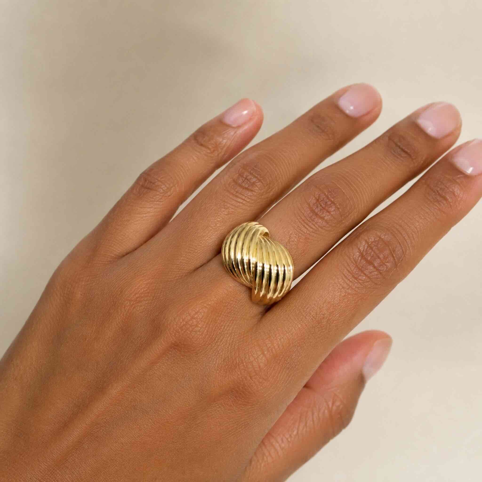 Anillo llamativo en Oro 10K con galería TuOro en mano de mujer trigueña, diseño acanalado ovalado con brillo elegante.