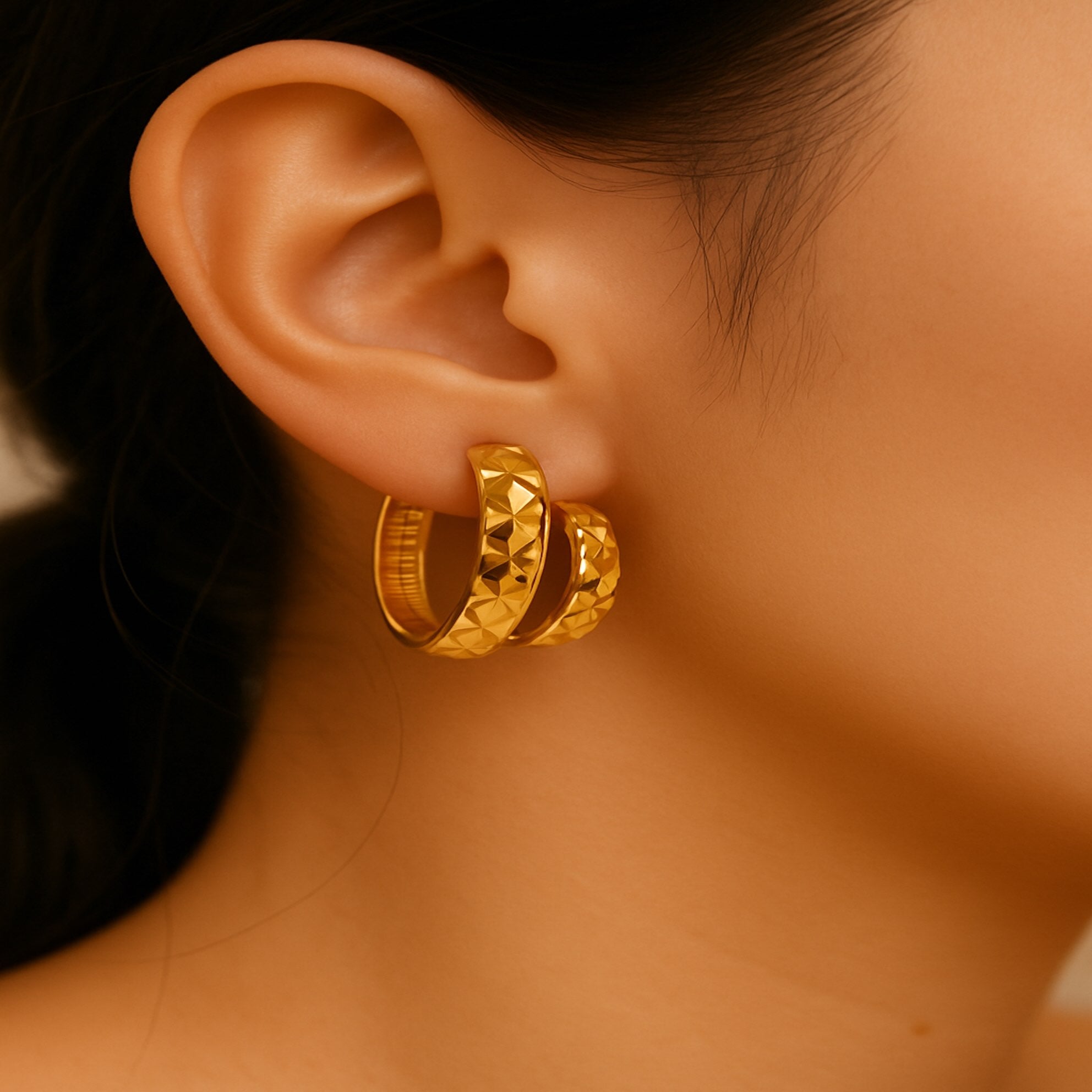 Arete huggie corto en oro 14K con diseño de corte diamante amarillo, para comparar,en oreja de modelo para mostrar proporción real