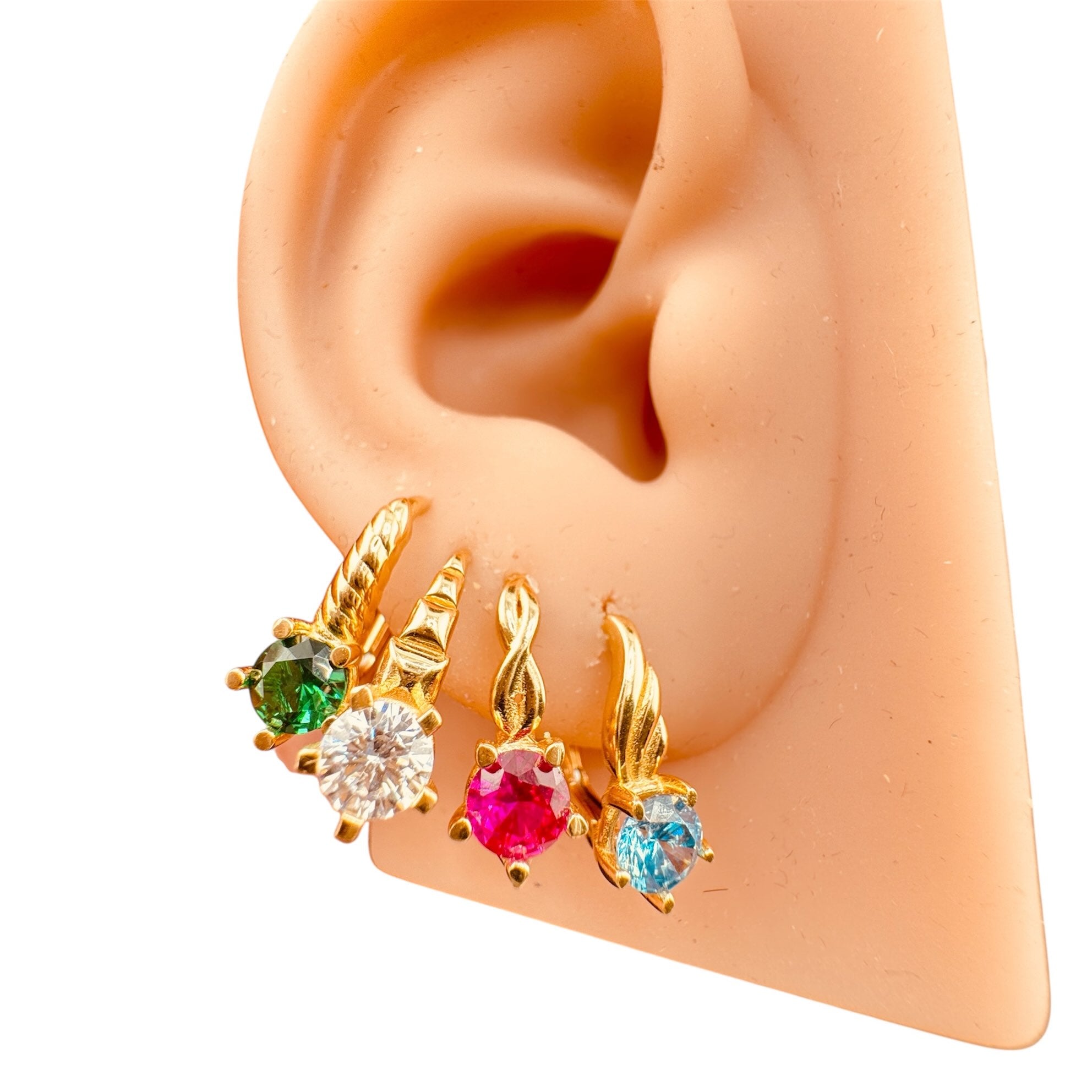 Aretes cortos en oro de 14 quilates con cierre de presión y zirconias en colores blanco, verde esmeralda, azul y rojo, mostrados en oreja para referencia de tamaño y estilo