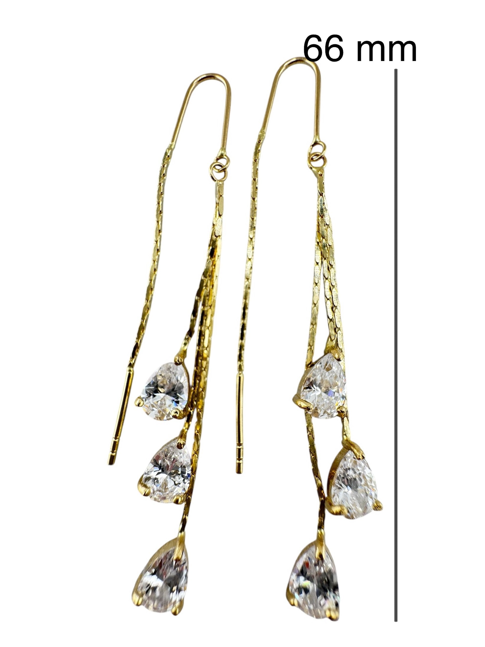 Par de aretes enhebradores largos en oro 14K de 66 mm con circonias en forma de gota, diseño moderno y elegante.