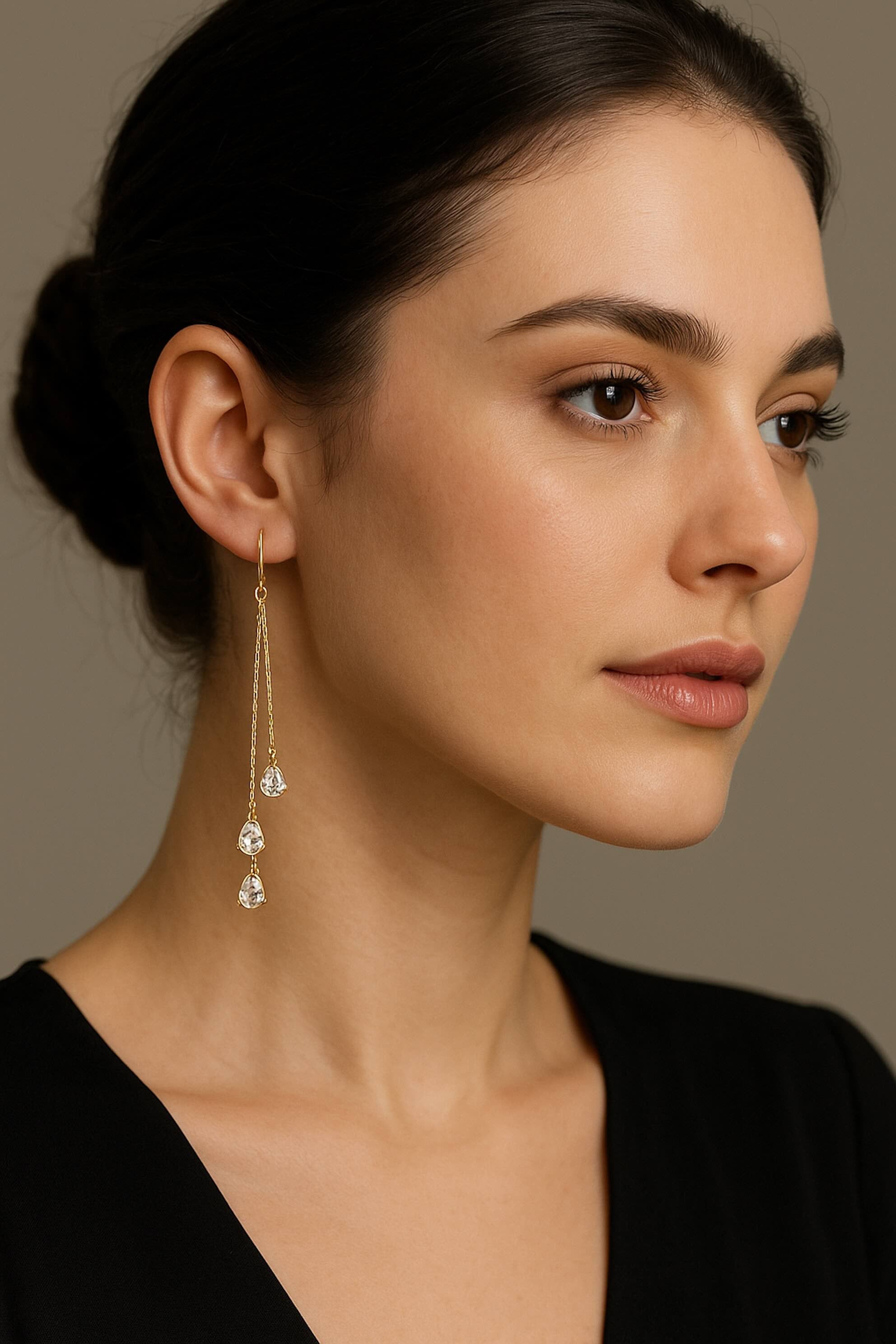 Modelo luciendo aretes enhebradores largos en oro 14K con circonias en forma de gota, joyería elegante y moderna.