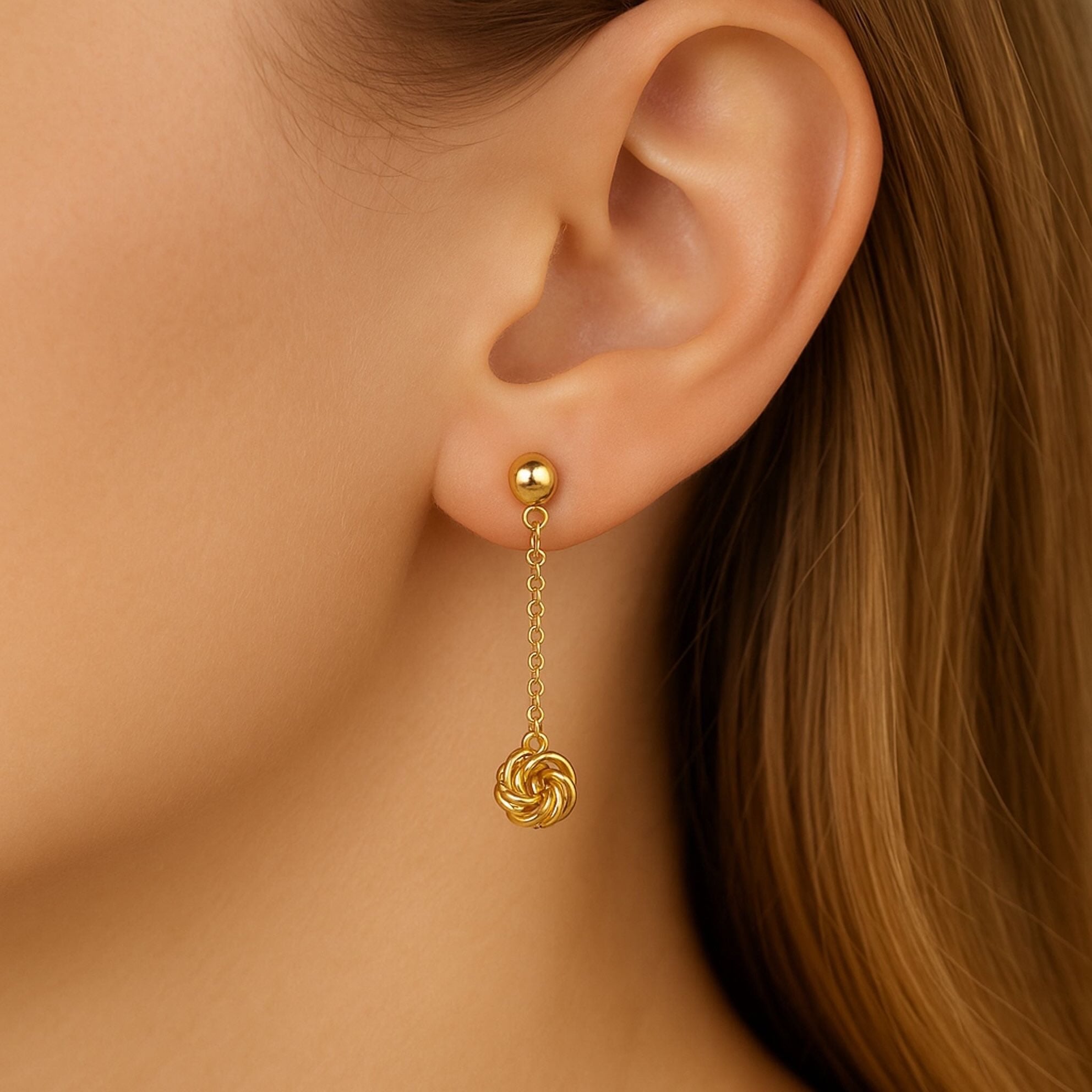 Arete largo en oro 14 kilates con cierre mariposa y colgante de nudo trenzado, joyería elegante para mujer