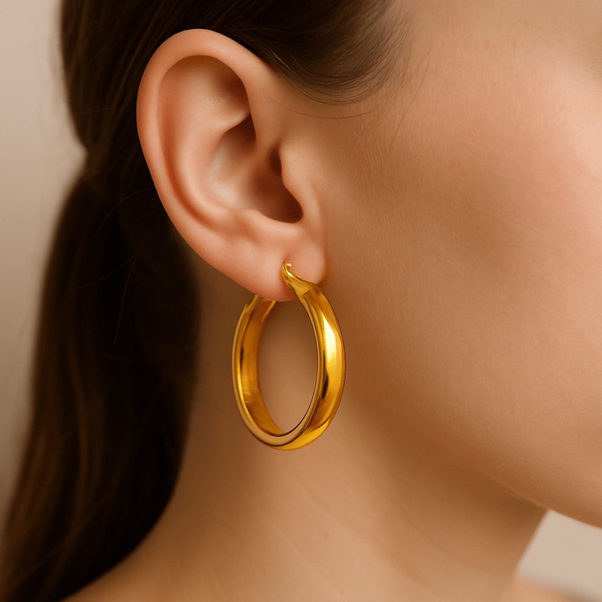 Argollas lisas media caña en oro 14K tamaño grande, con diseño clásico y terminación espejo, mostradas en oreja de modelo – Joyería TuOro