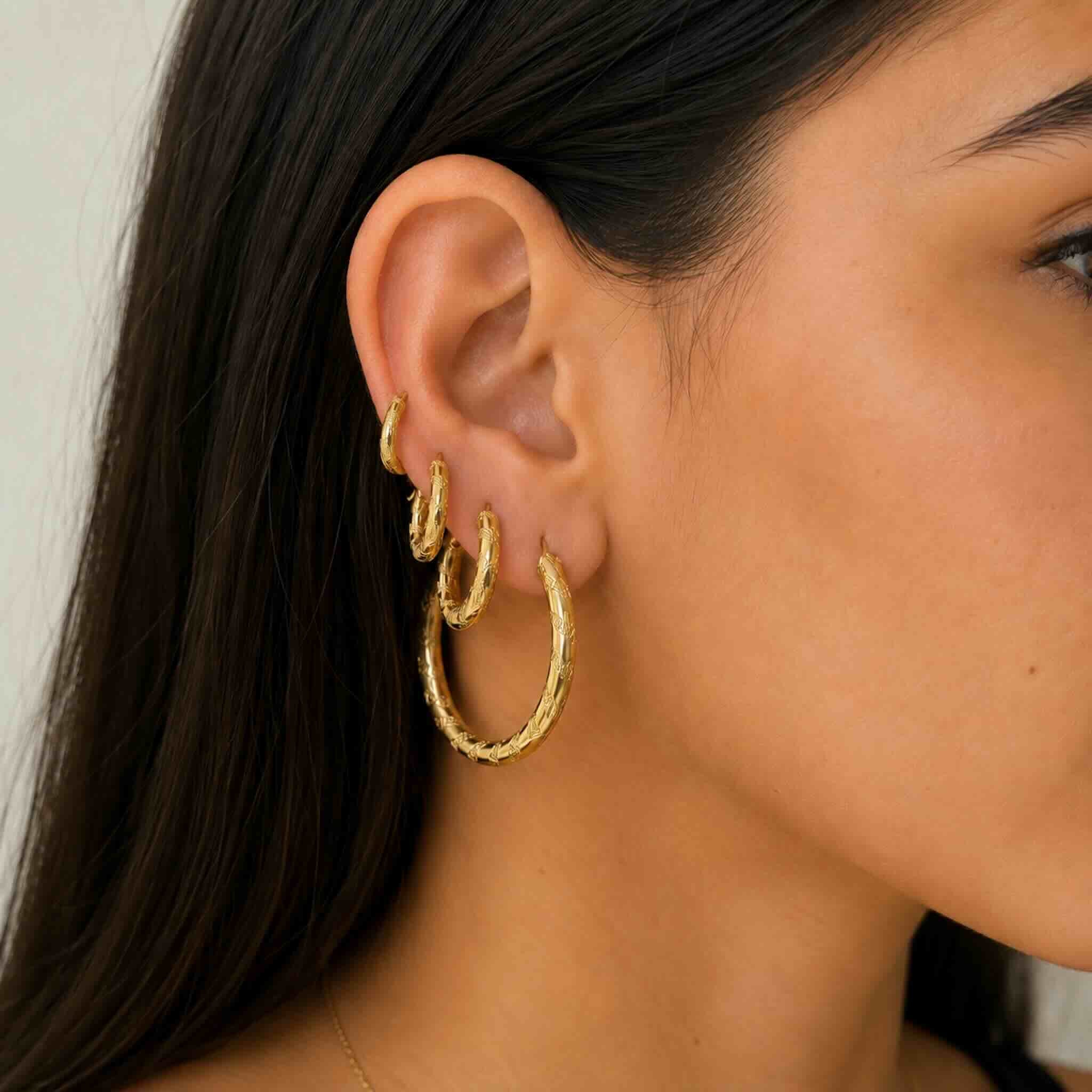 Detalles de argollas torcidas con textura en oro 10K en modelo joven exibiendo cuatro partes de TuOro.