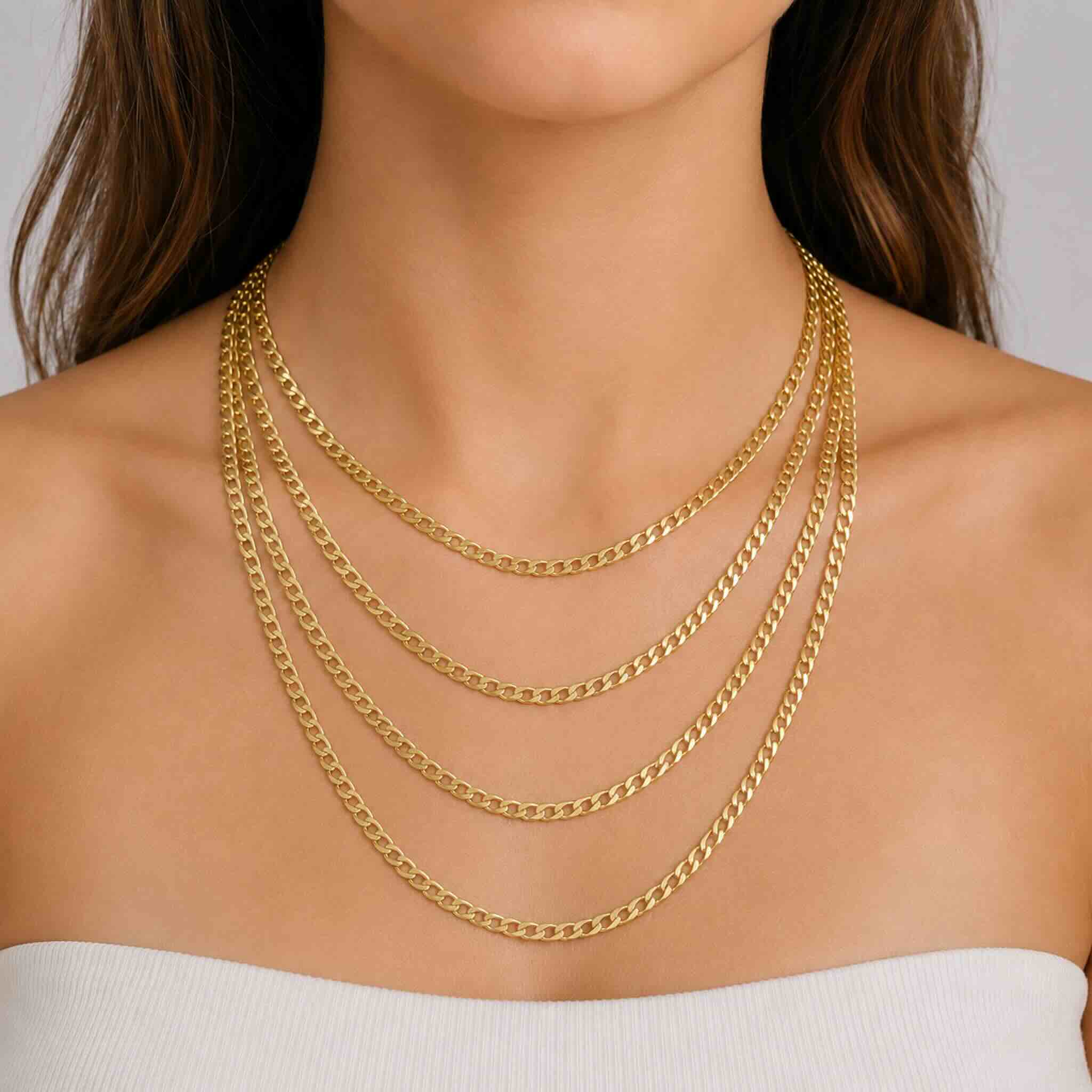 Cuatro cadenas cubanas de oro 10K de 4 mm en largos de 18, 20, 22 y 24 pulgadas sobre el cuello de una mujer joven.