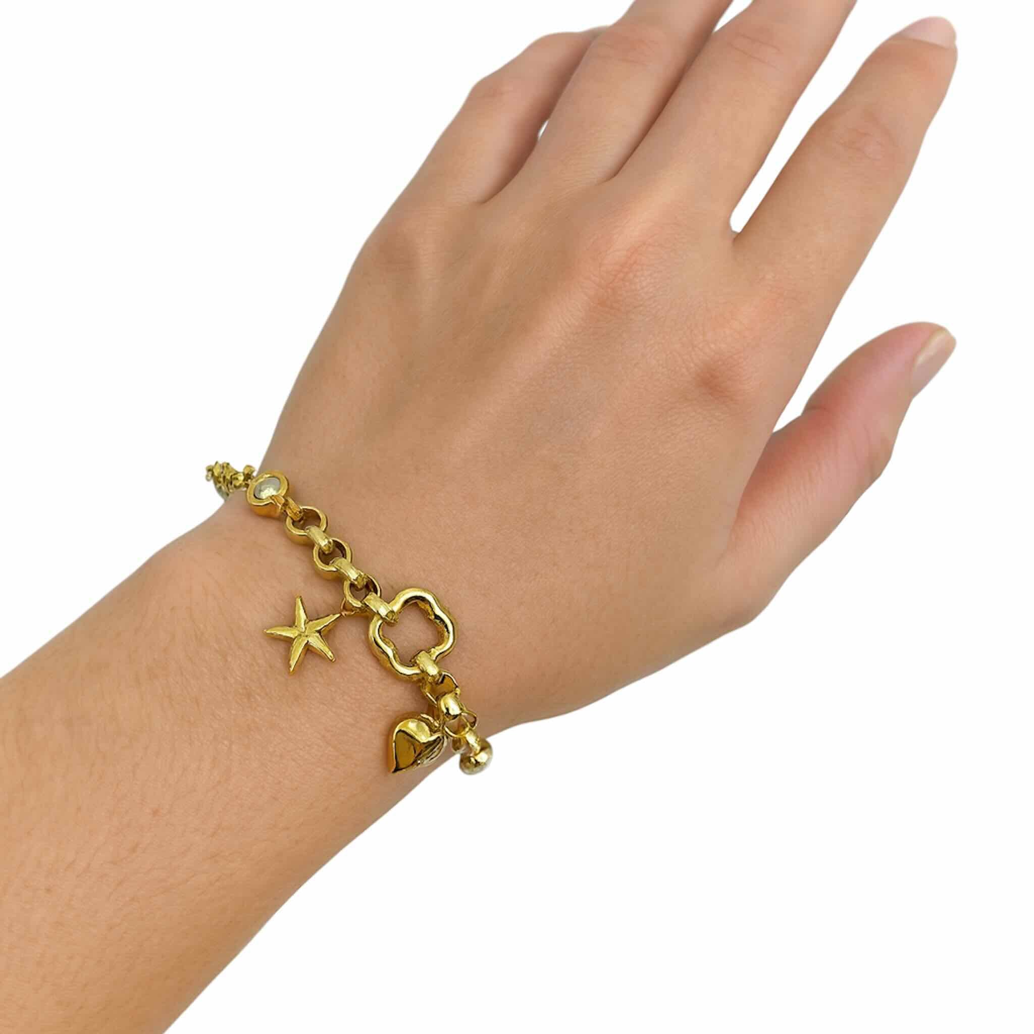 Pulsera de Oro 14K con dijes decorativos colocada en la muñeca, diseño elegante de TuOro