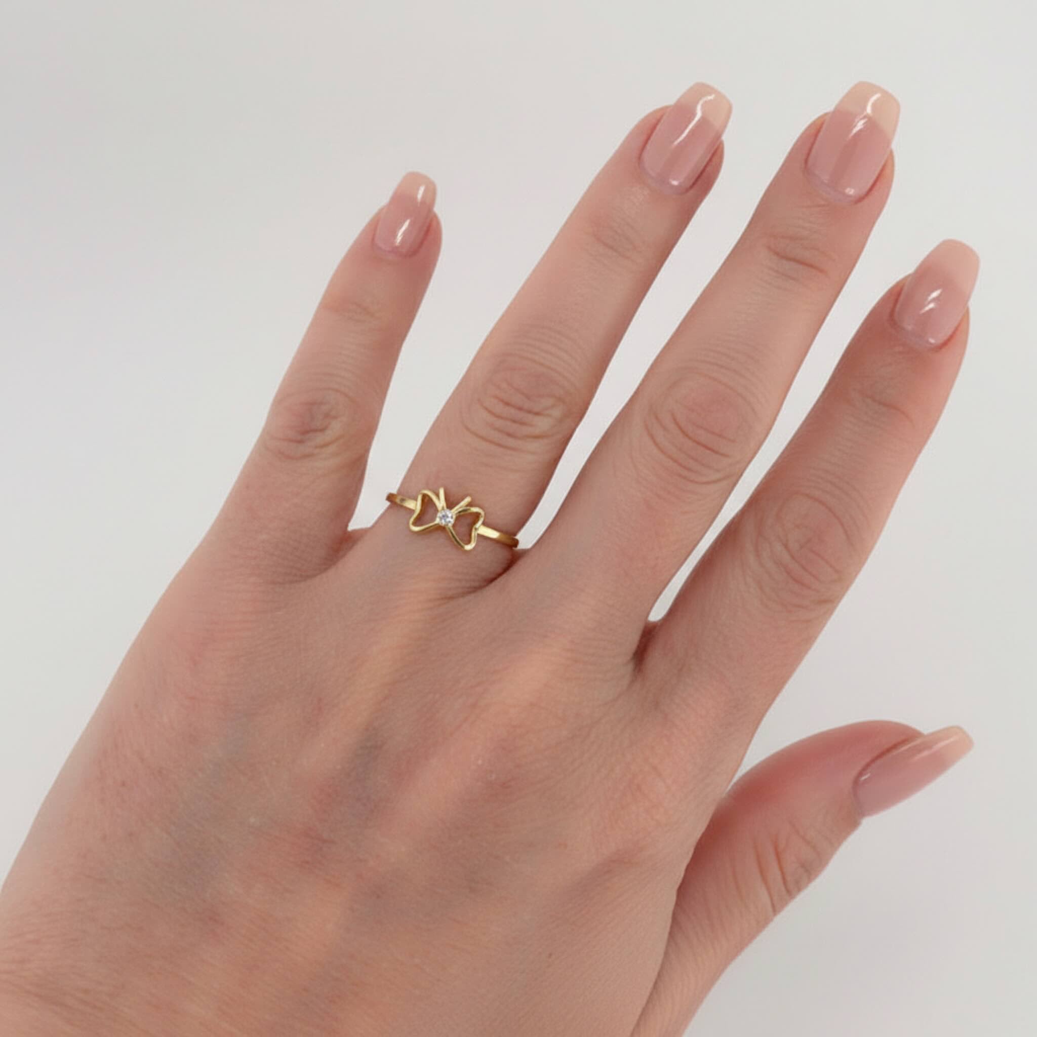Anillo fino en Oro 14K con lazo delicado y piedra brillante lucido en mano femenina, diseño exclusivo de Anillos Finos en Oro 14K de TuOro.