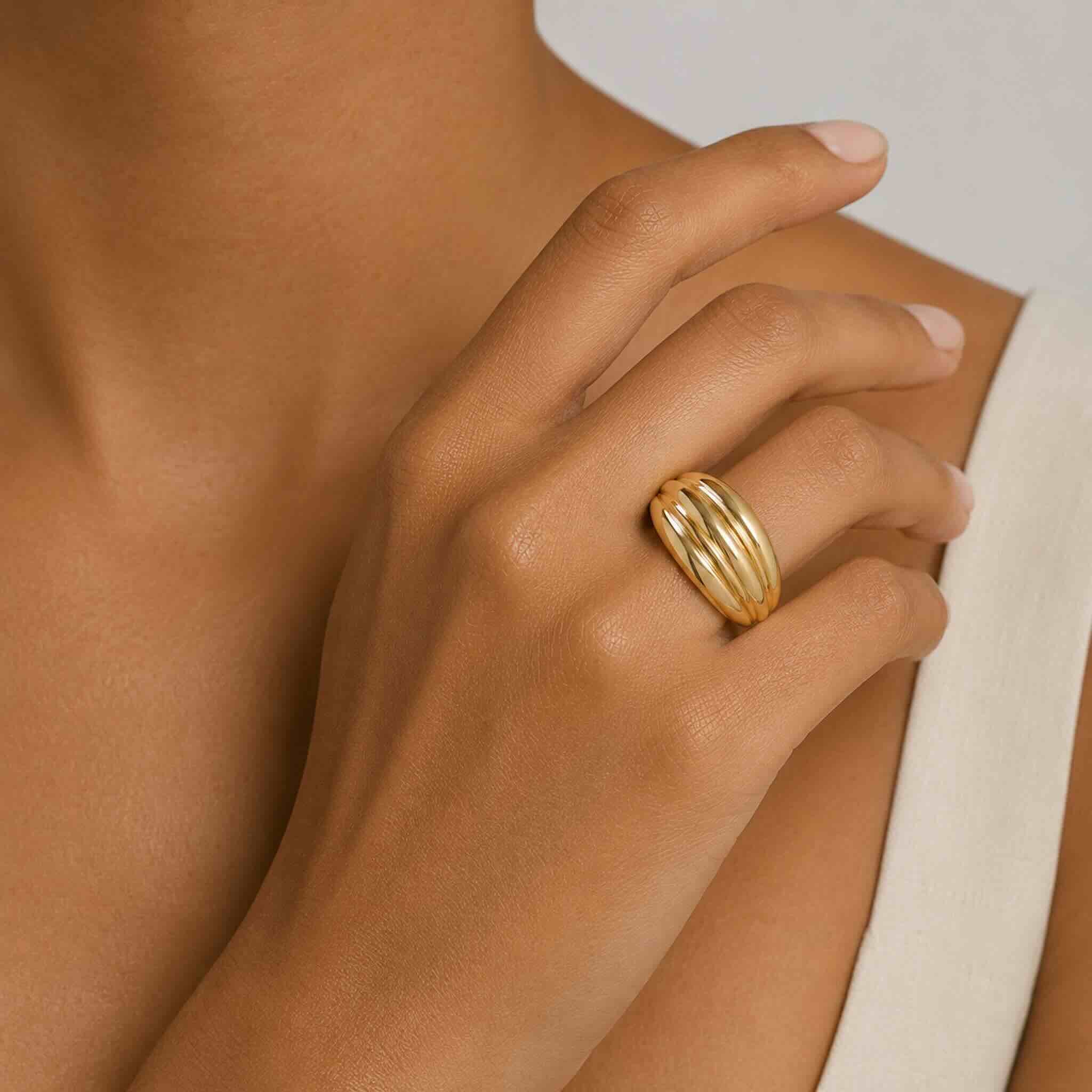 Anillo llamativo en Oro 10K con galería y diseño acanalado de líneas curvas, puesto en una mano femenina elegante, TuOro®.