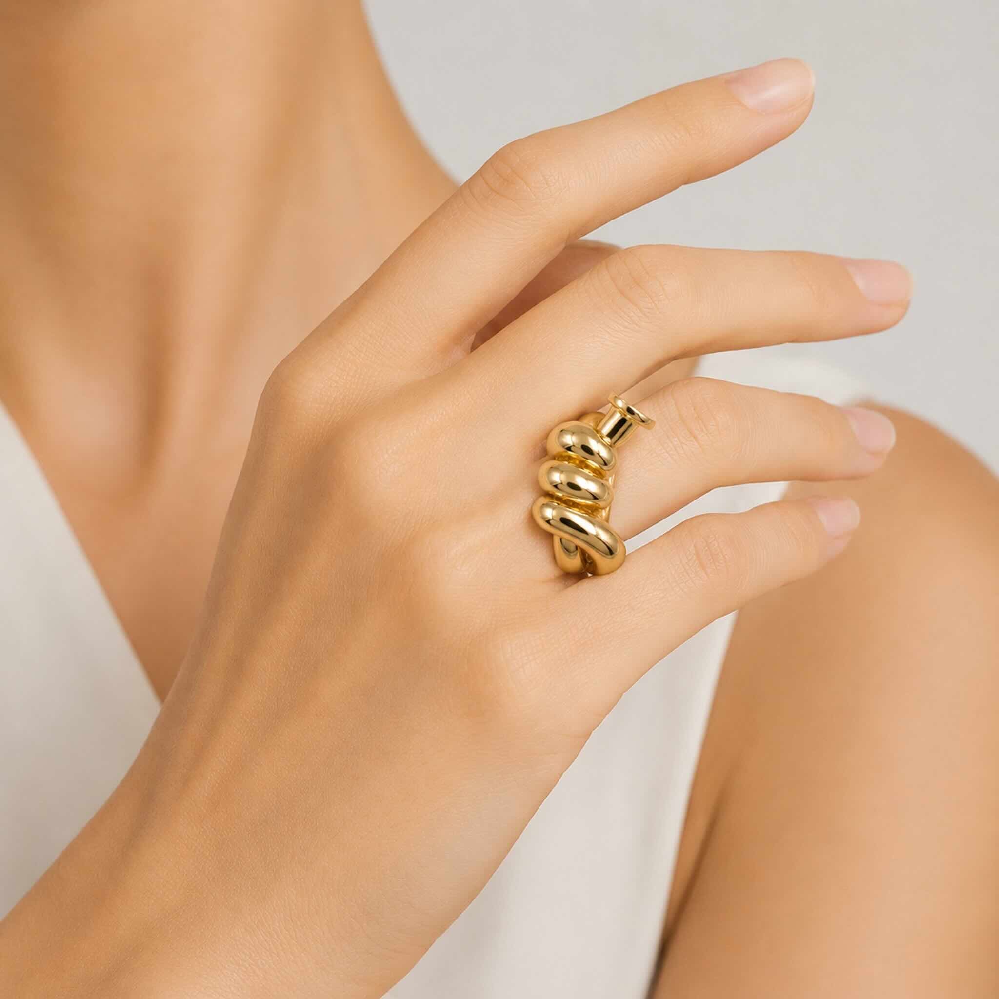 Anillo llamativo en Oro 10K con galería y diseño escultural de espiral tubular, puesto en la mano de una mujer elegante, TuOro®.