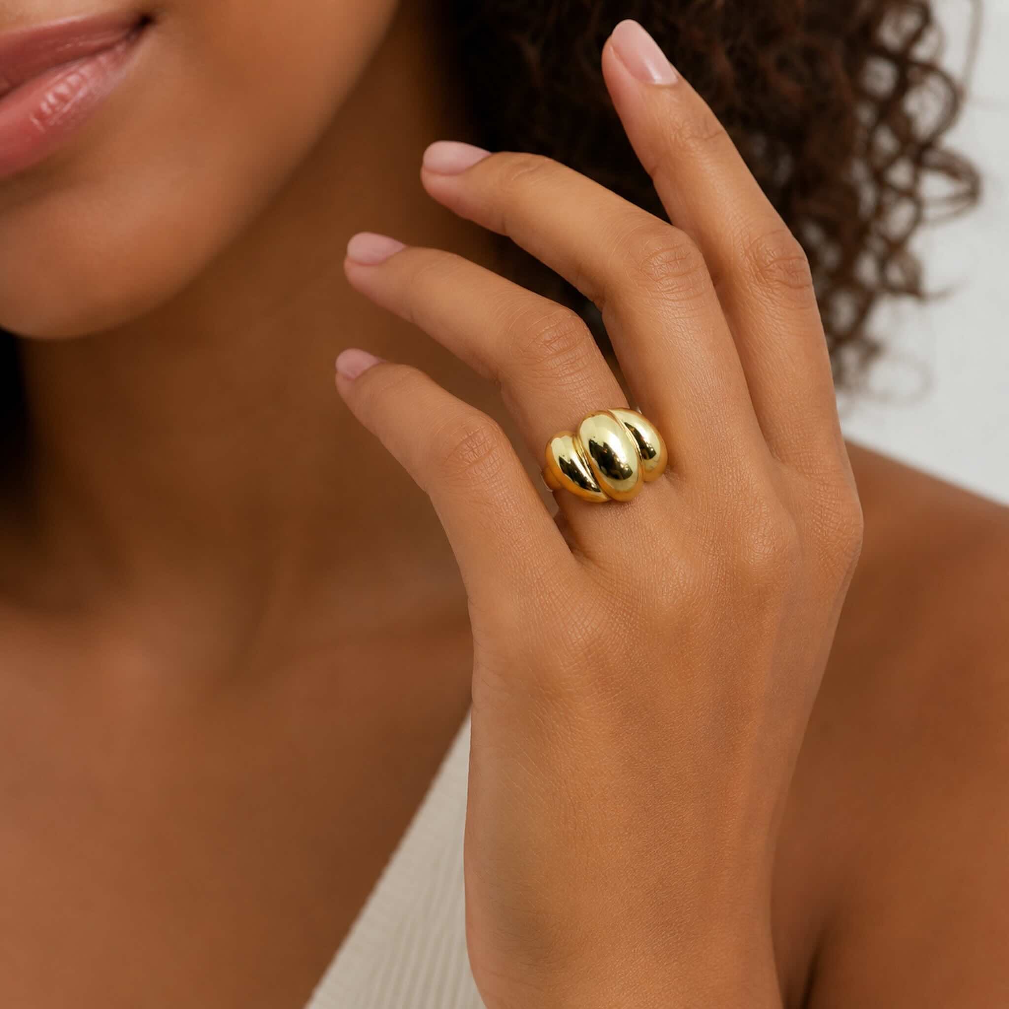 Anillo llamativo en Oro 10K de diseño voluminoso modelado en la mano de una mujer mulata joven, foto elegante de catálogo de TuOro®.