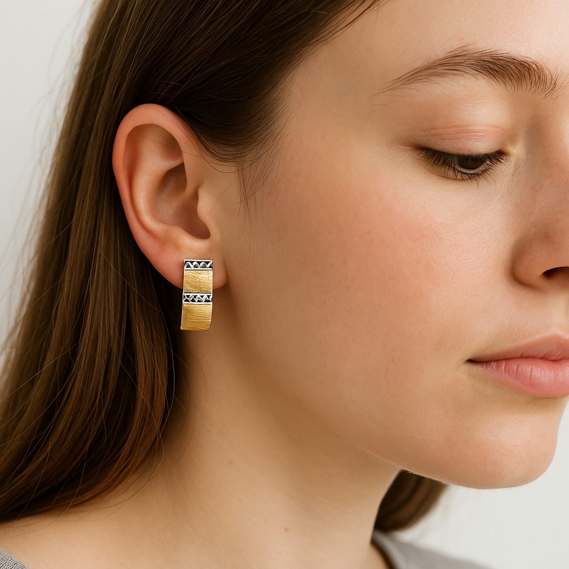 Arete corto con cierre catalán en oro de 14 quilates, diseño geométrico de 21 x 7 mm, mostrado en la oreja para apreciar su tamaño y estilo elegante.