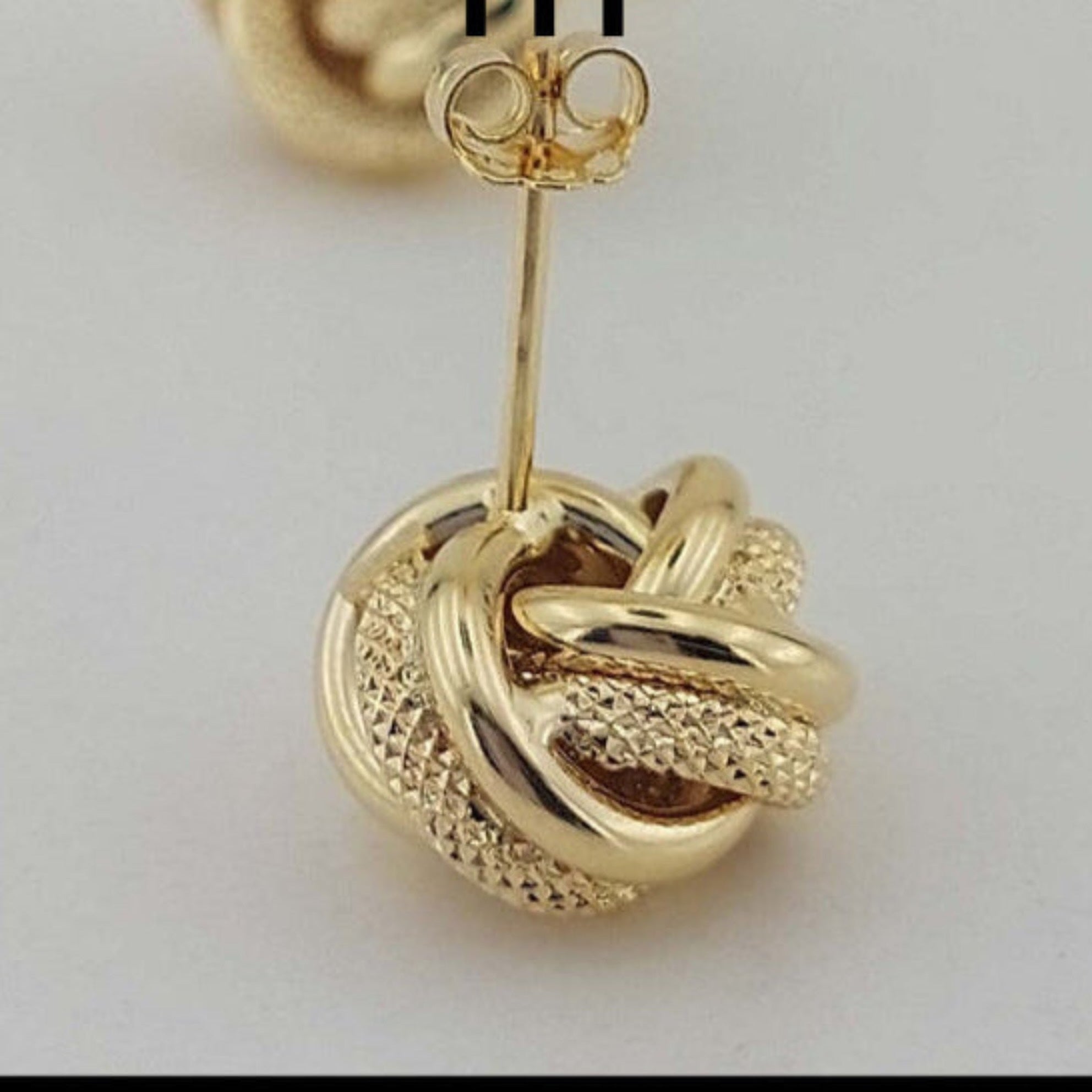 Detalle ampliado del cierre a presión de arete Nudo del Amor en oro 14K con acabado texturizado y liso

