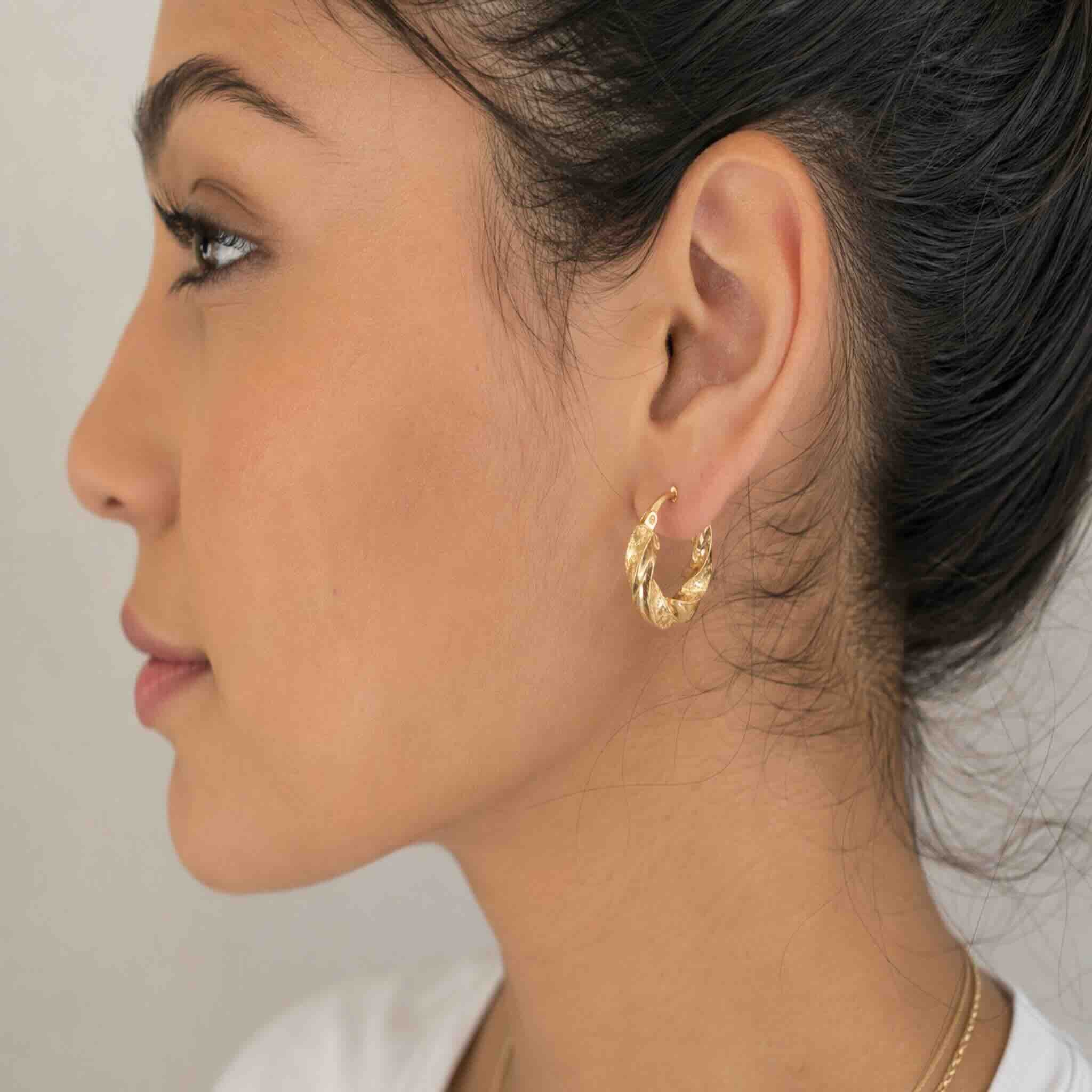 Mujer joven de perfil usando argolla torcida de Oro 10K de 5 mm con acabado brillante y texturizado