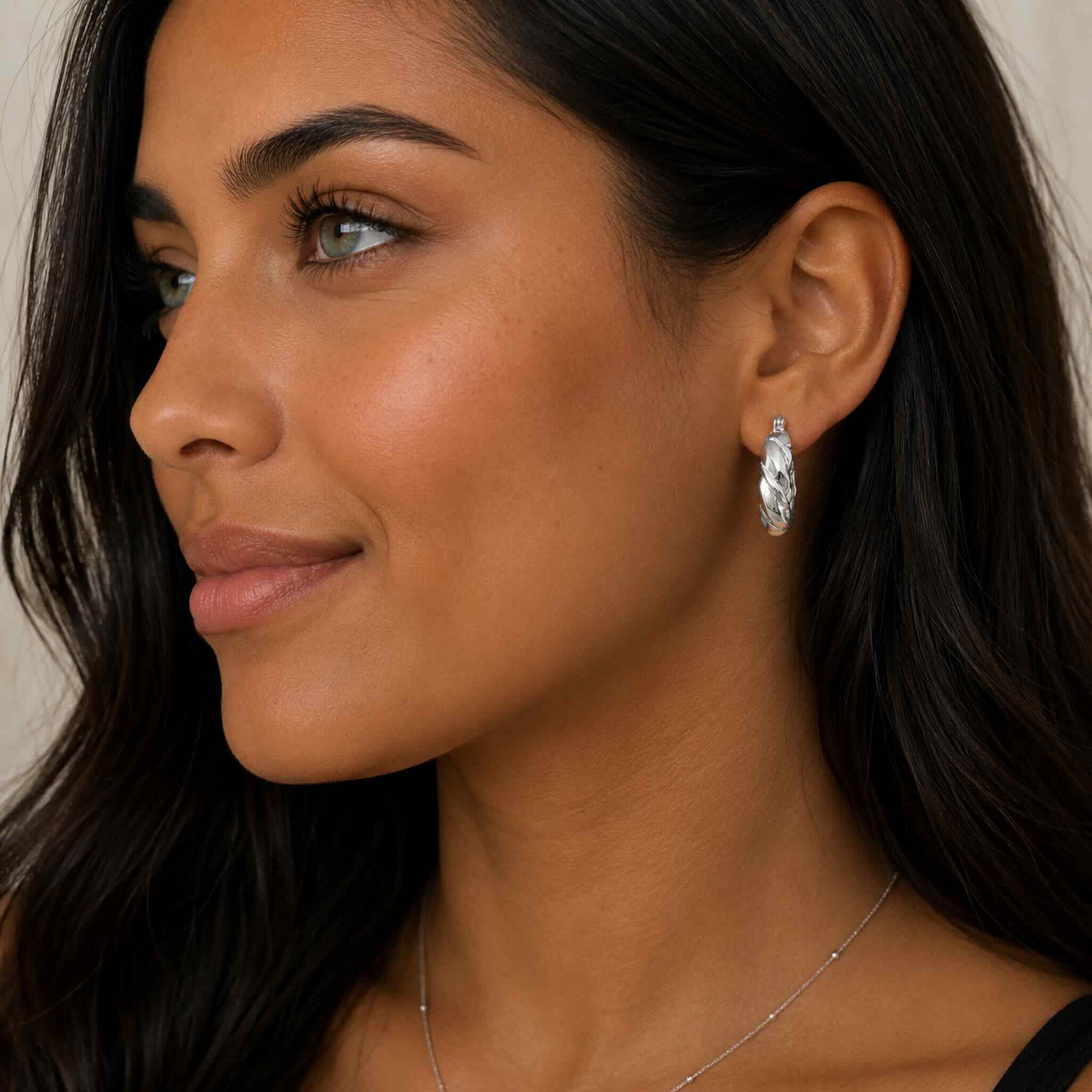 Mujer trigueña de ojos claros usando argollas torcidas de Plata 925 con Rodio, acabado brillante y estilo moderno – TuOro