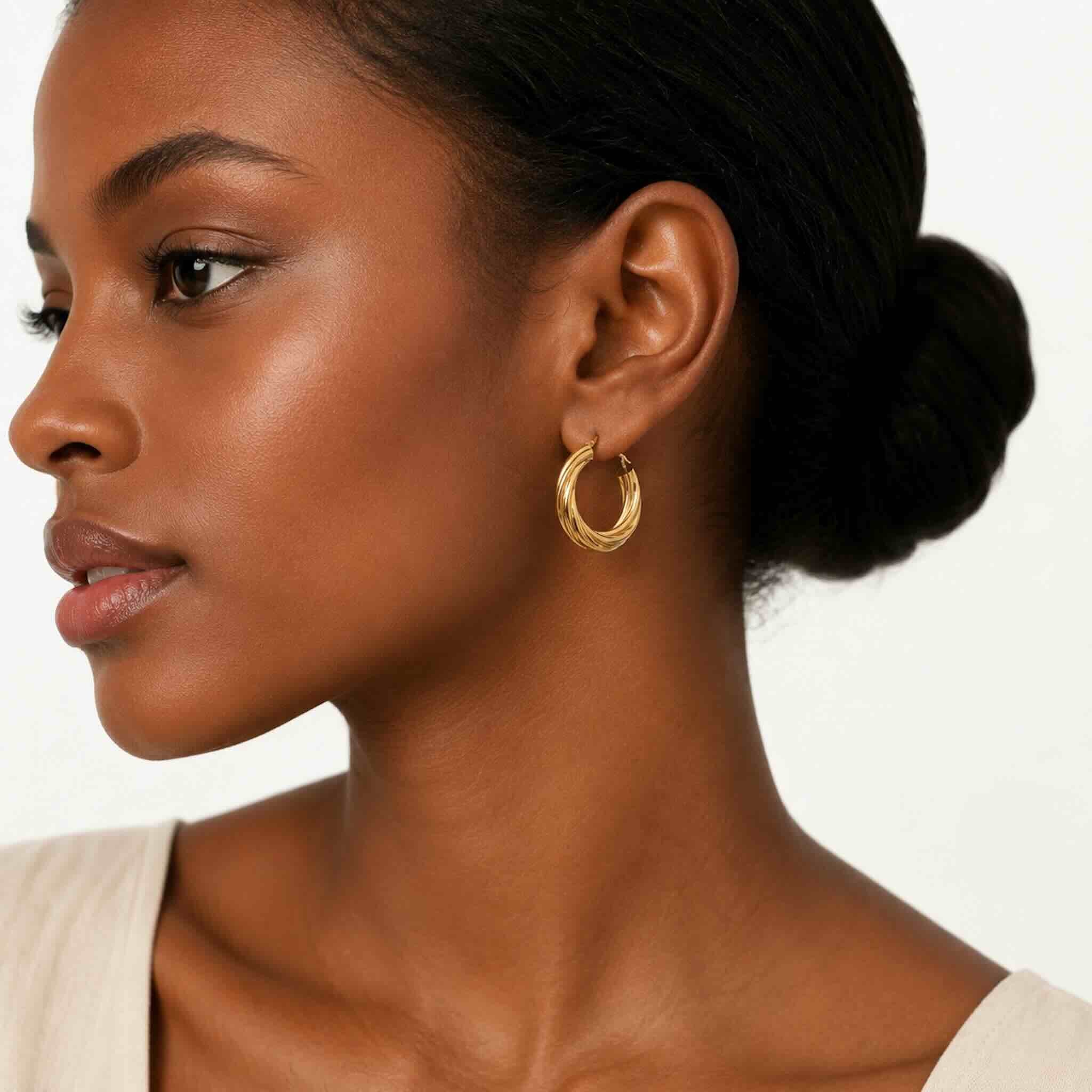 Mujer joven de tez oscura con argollas torcidas lisas en oro 10K de 4.8 mm y 24.5 mm de diámetro.