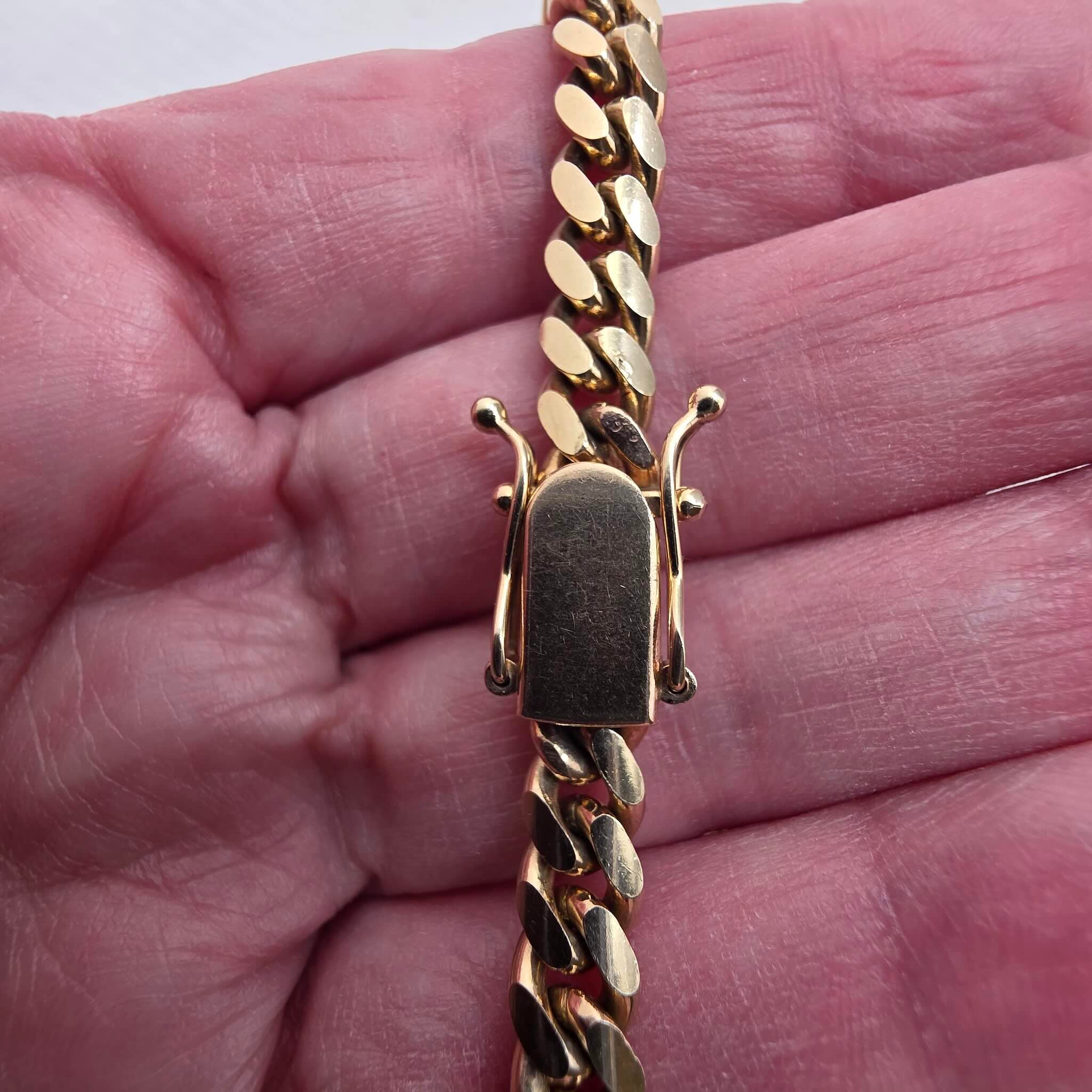 Cadena con cierre de caja en Oro 10K, Cuban Link en 6 mm de ancho, mostrando el tranque en una mano.TuOro.