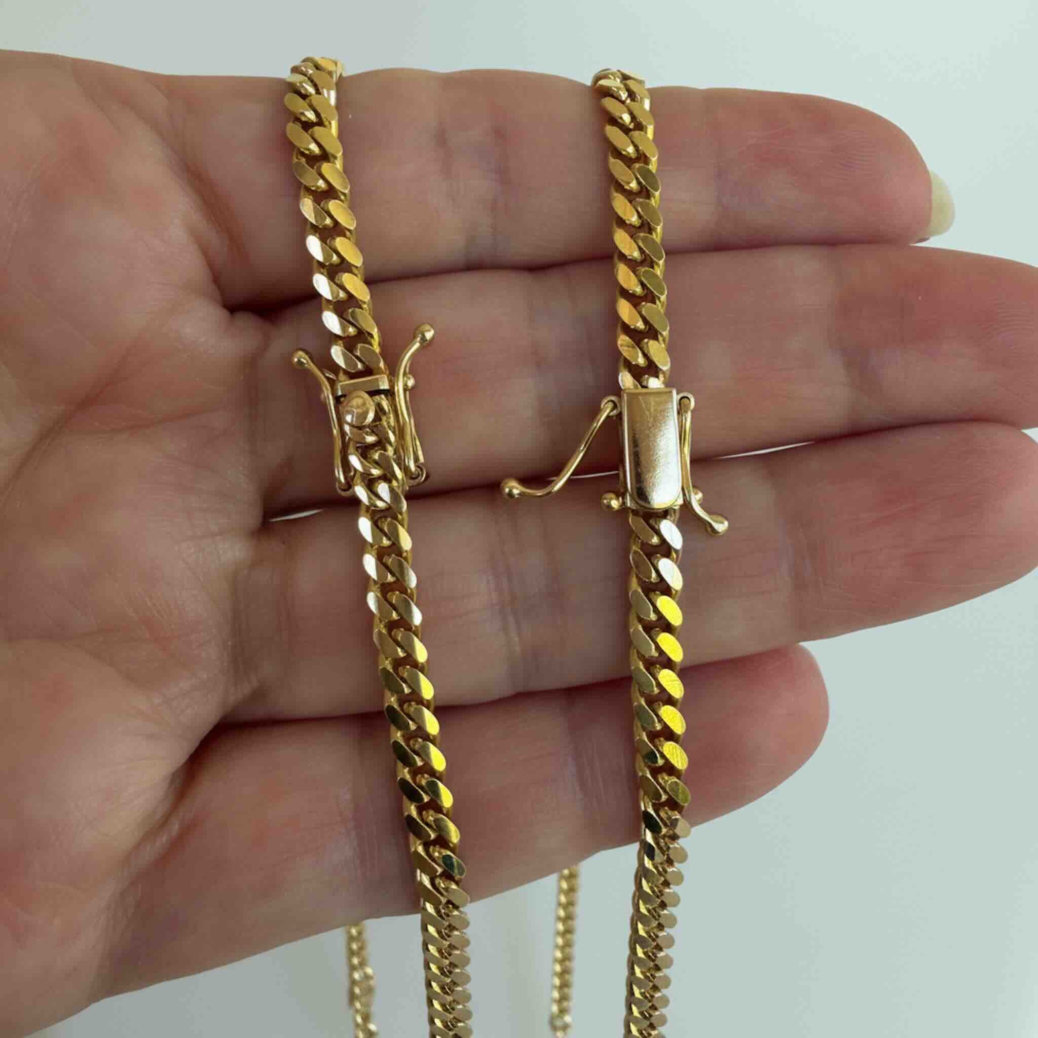Primer plano de cadenas Cuban Link de oro 10K TuOro sobre una mano, mostrando los cierres de caja con seguros laterales.