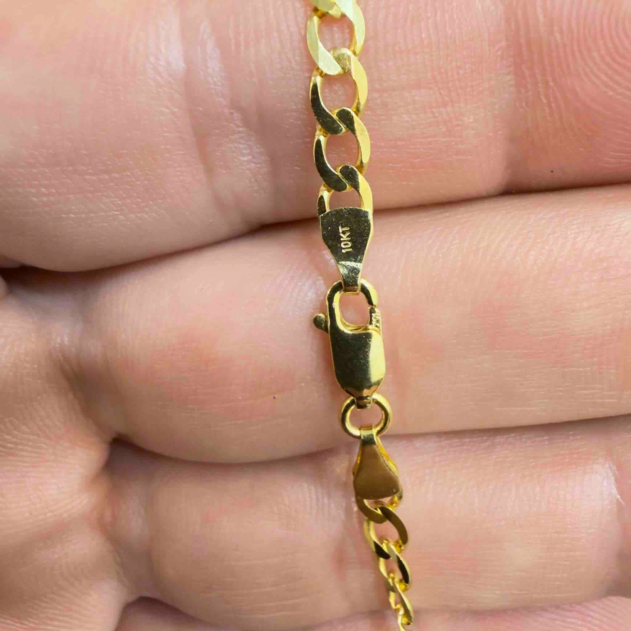 Cadena cubana de oro 10K de 4 mm y con cierre de langosta sobre la mano de un hombre mostrando detalles.
