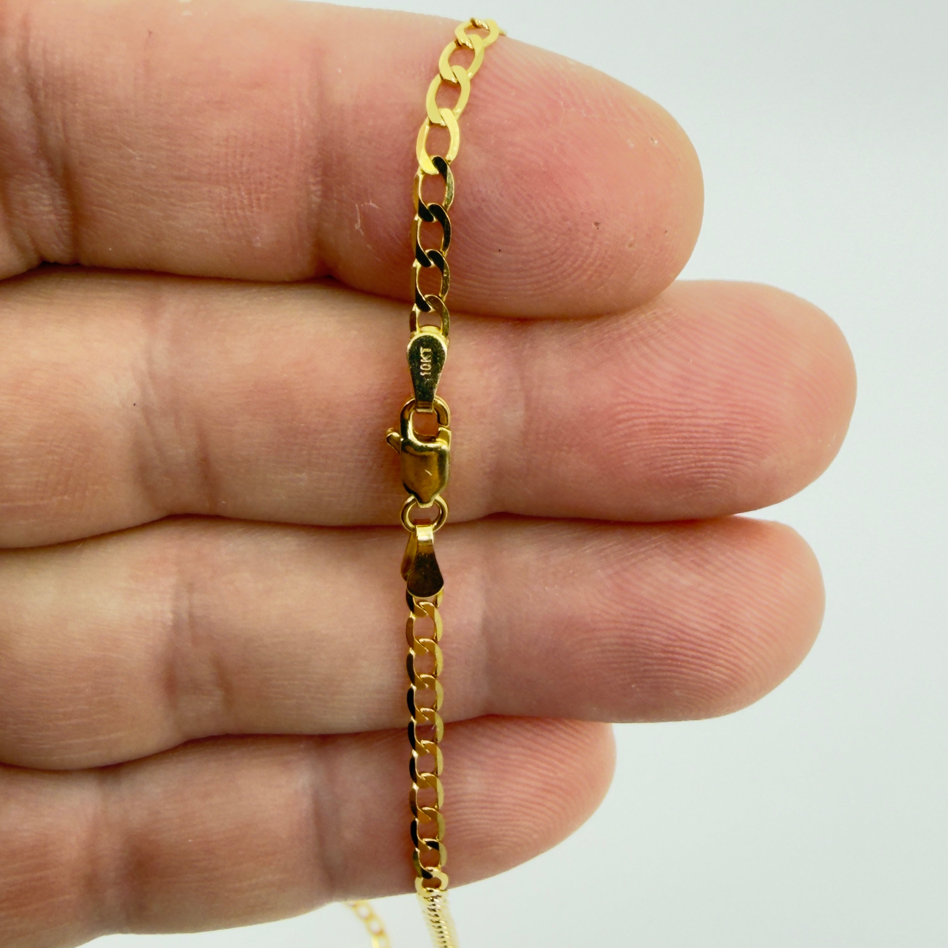 Cadena cubano-italiana de oro 10K de 2.5 mm y mostrando detalles del cierre en una mano.