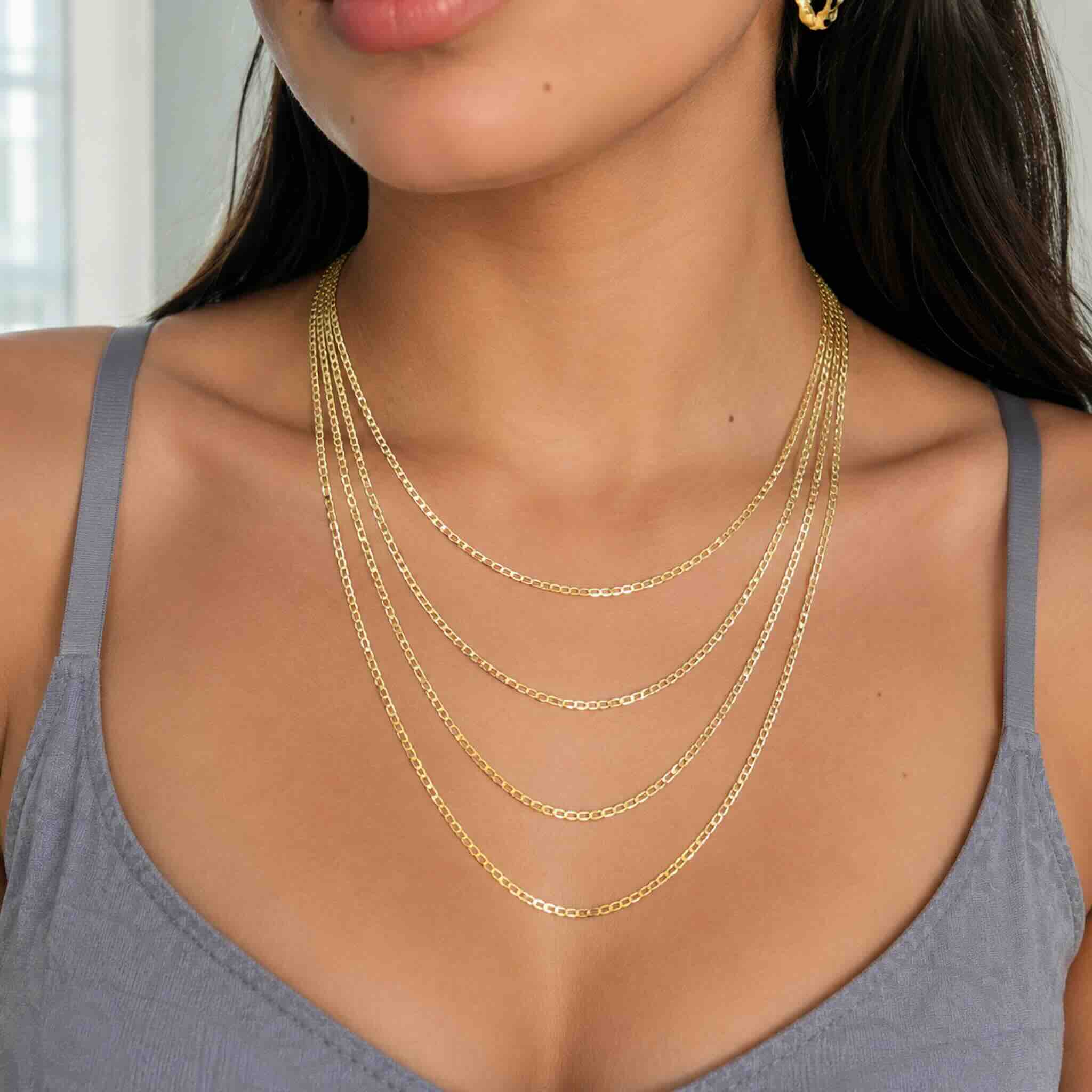 Mujer joven luciendo cuatro cadenas cubano-italianas de oro 10K de 2.5 mm en largos de 18, 20, 22 y 24 pulgadas.