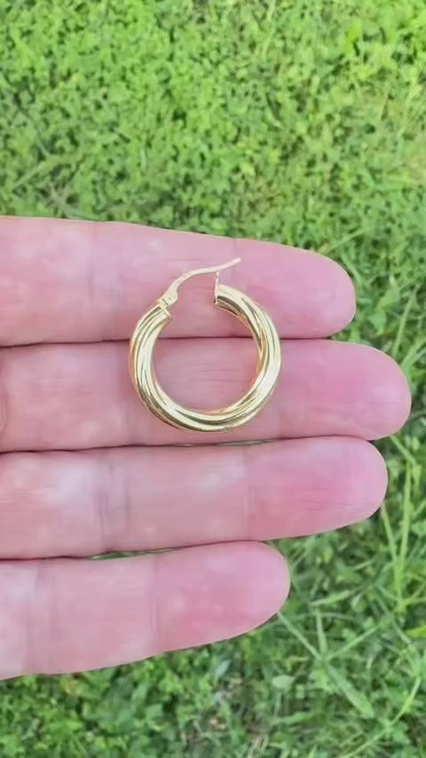 Video corto de argolla torcida lisa de oro 14K colocada sobre los dedos para mostrar el tamaño