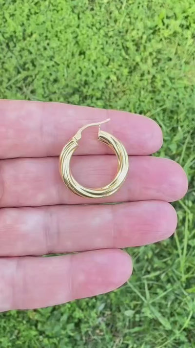 Video corto de argolla torcida lisa de oro 14K colocada sobre los dedos para mostrar el tamaño