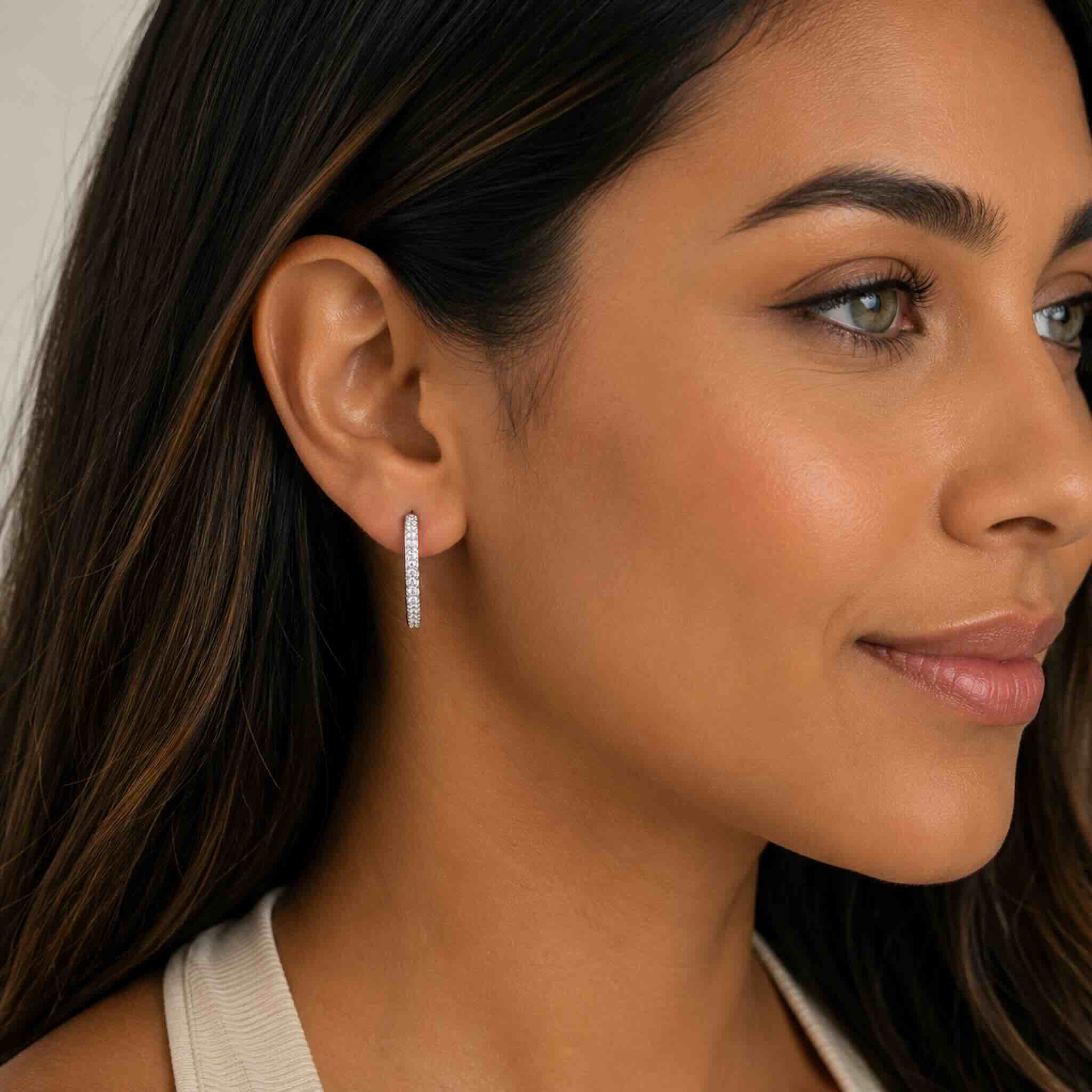 Modelo usando Aretes Huggie de Plata 925  con piedras brillantes, diseño elegante y moderno para uso diario, TuOro.