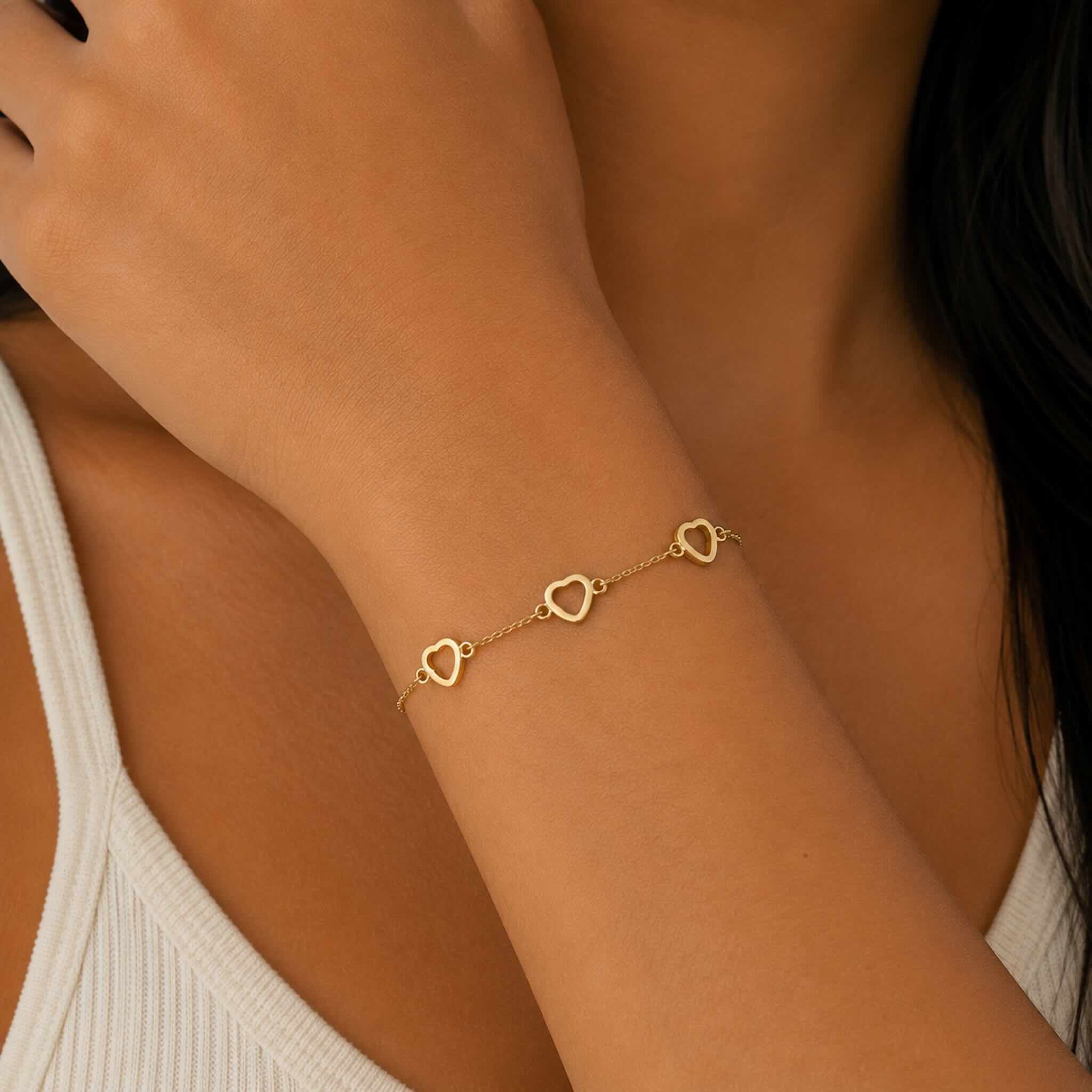 Vista completa de la pulsera delicada de oro 10K con corazones abiertos usada por modelo joven en TuOro®.
