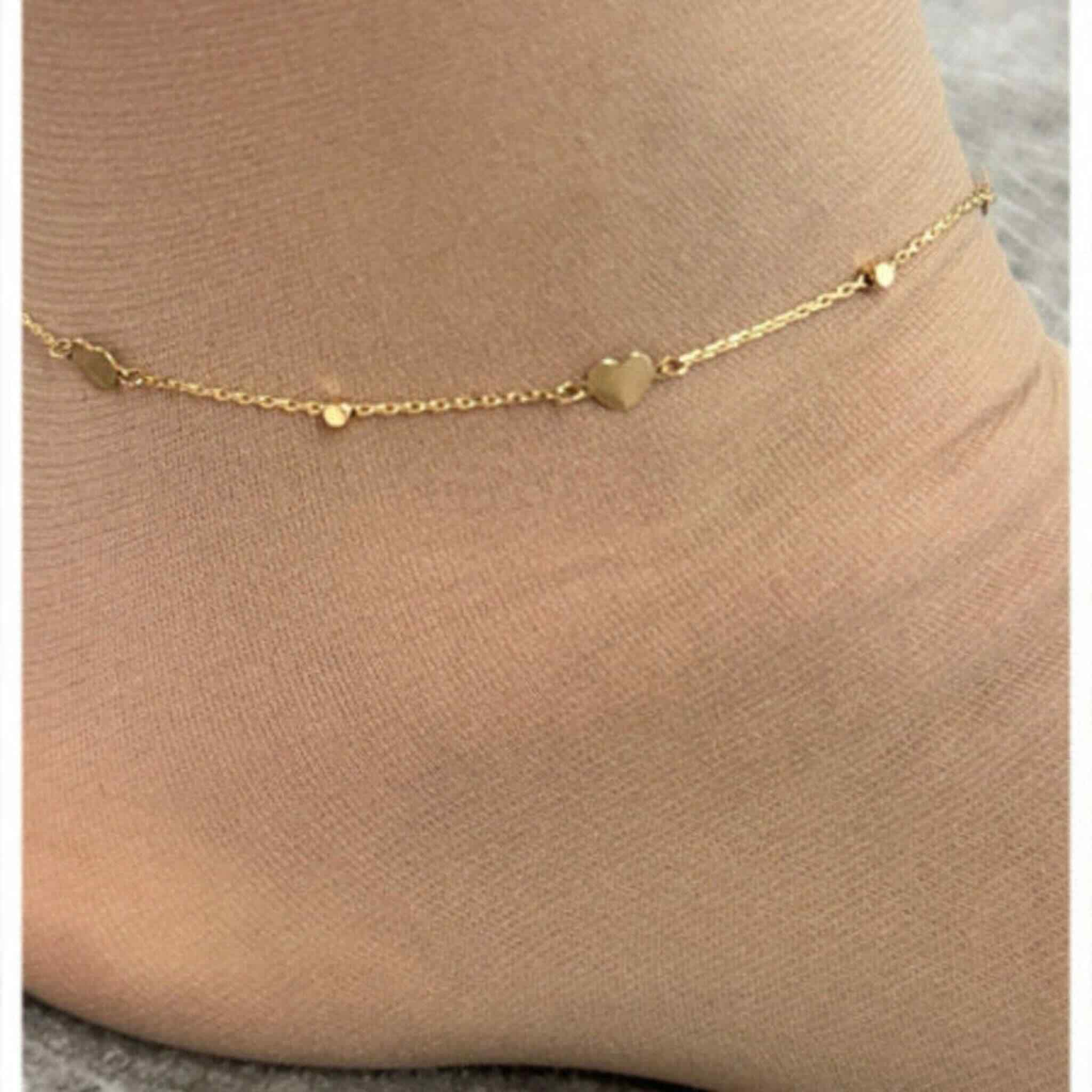 Tobillera fina en Oro 14K con corazón integrado en la cadena, lucida en el tobillo, diseño elegante de Joyería TuOro.