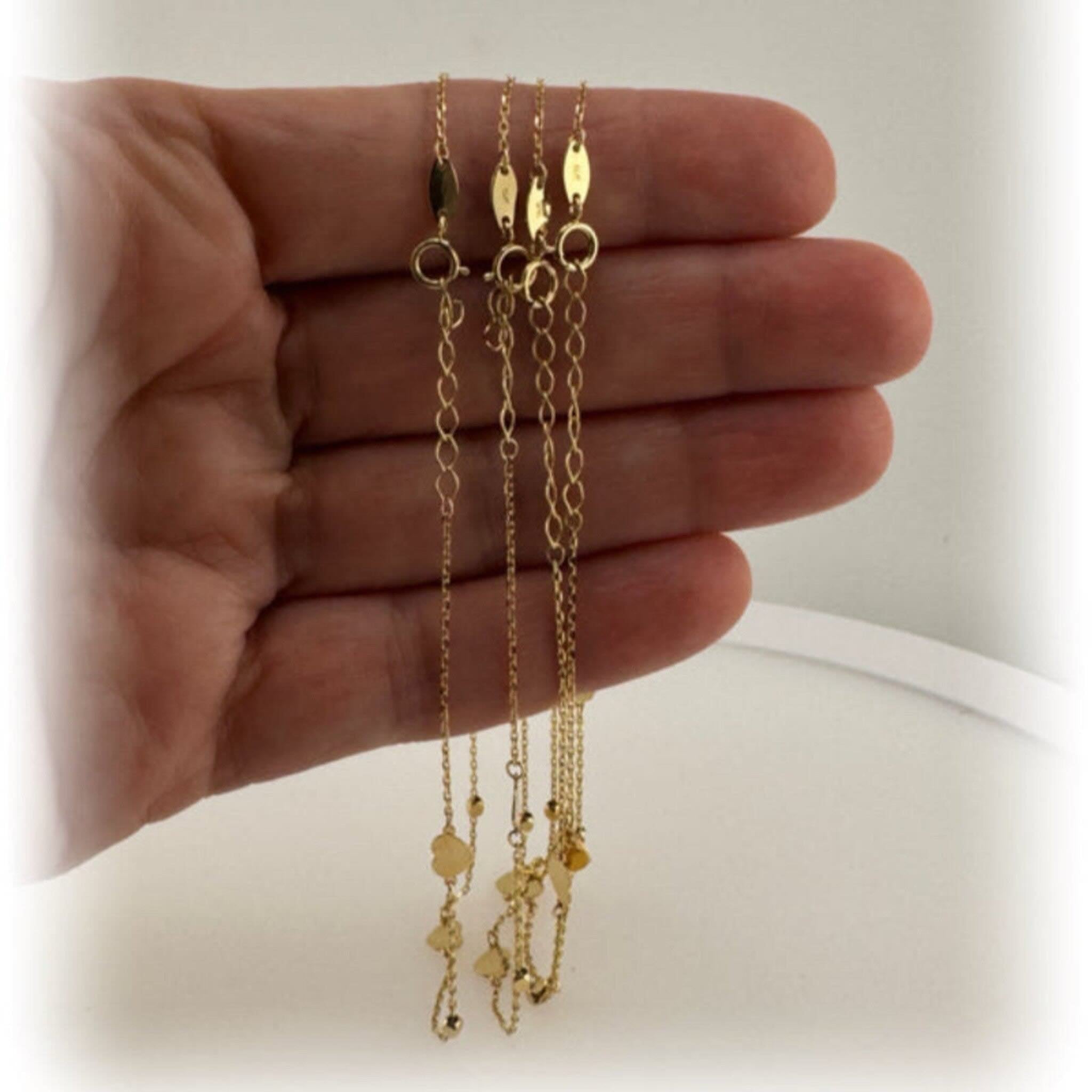 Tobilleras finas en Oro 14K con corazón, trébol y mariposa integrados, mostradas juntas en la mano, diseño elegante de Joyería TuOro.